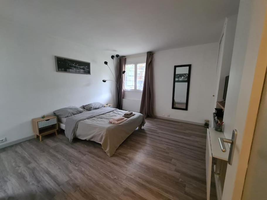 une chambre avec un lit et un parquet dans l'établissement Logement entier tout confort, à Saint-Cyr-lʼÉcole