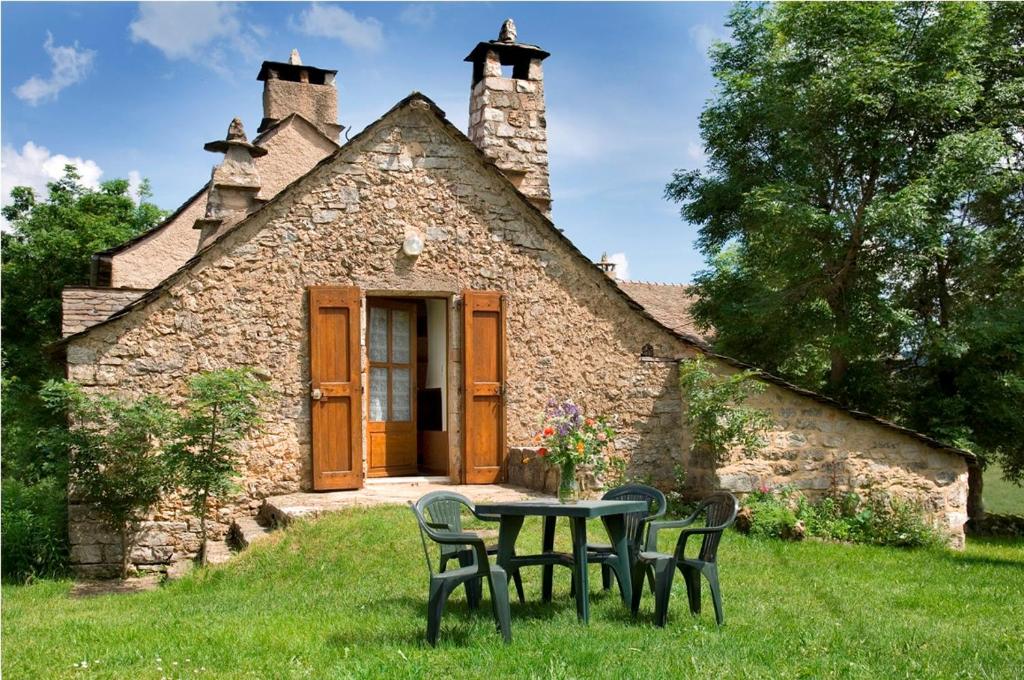 une table et des chaises devant un bâtiment dans l'établissement Gîte Le Petit Gîte 2/4 personnes à Valbelle, à Florac Trois Riviere