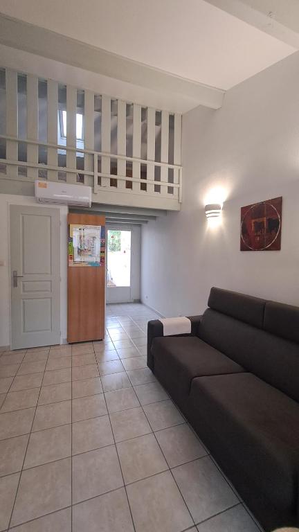 un salon avec un canapé noir et une cuisine dans l'établissement Studio duplex avec extérieur, à Aigues-Mortes