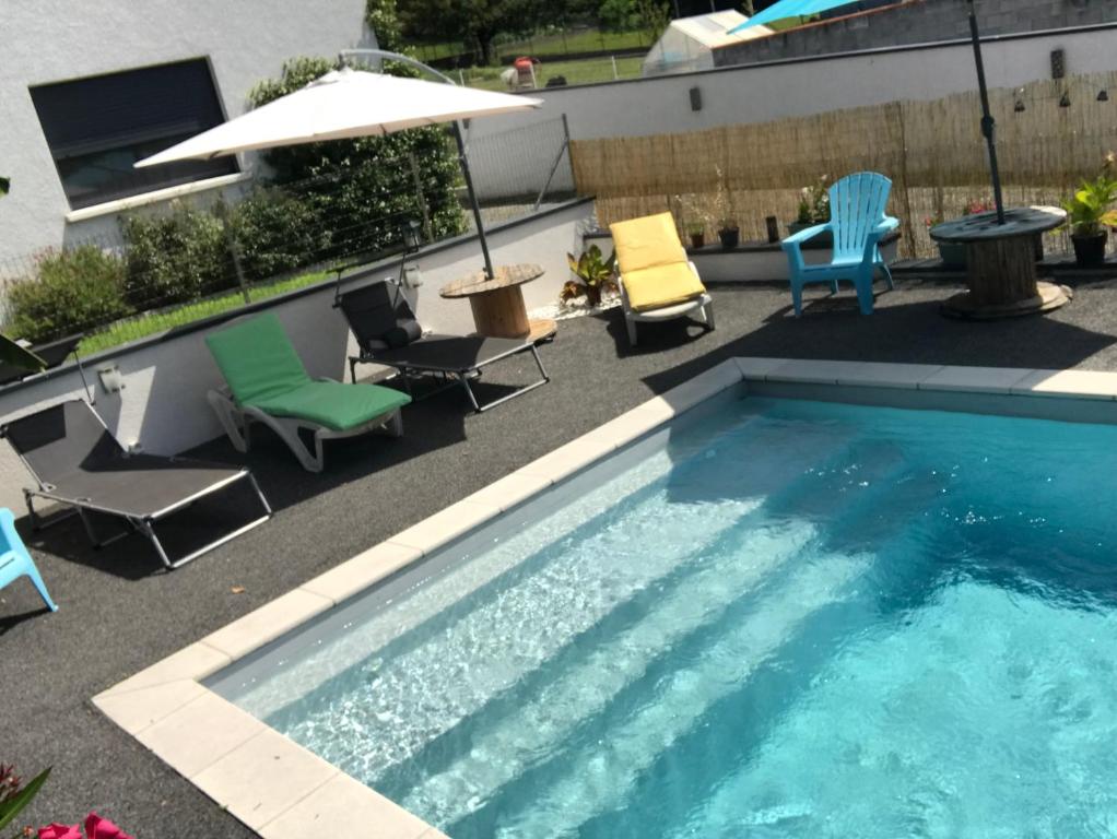 - une piscine avec des chaises, une table et un parasol dans l'établissement Bella vita, à Arthès