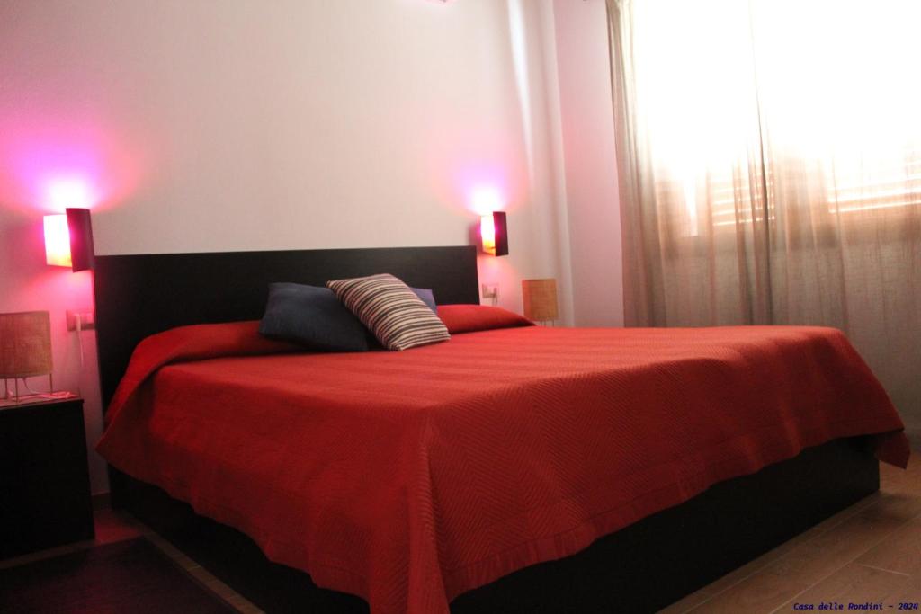 a bedroom with a red bed with a red blanket at Casa delle rondini in SantʼAnna Arresi