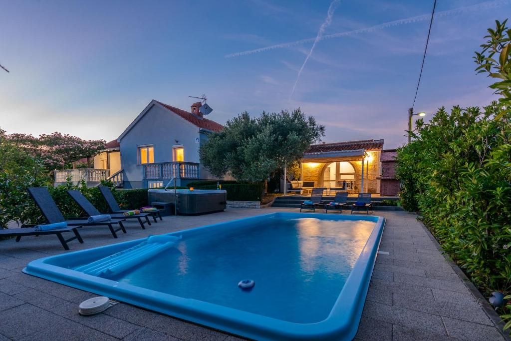a pool in a yard with chairs and a house at HOLIDAY HOUSE LAVANDA in Gornji Zemunik