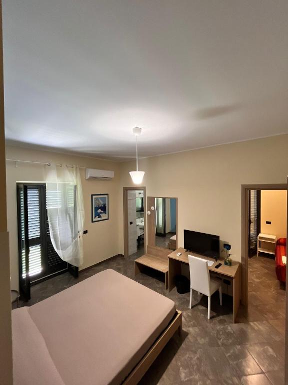a room with a bed and a desk and a television at La Flacca Rooms in Sperlonga