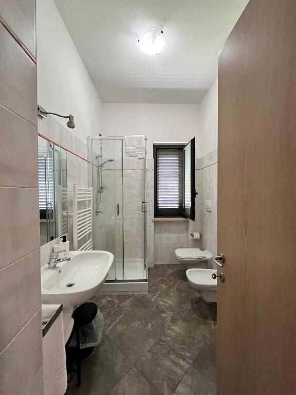 a bathroom with two sinks and a shower and two toilets at La Flacca Rooms in Sperlonga