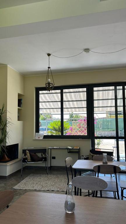 a living room with tables and chairs and windows at La Flacca Rooms in Sperlonga