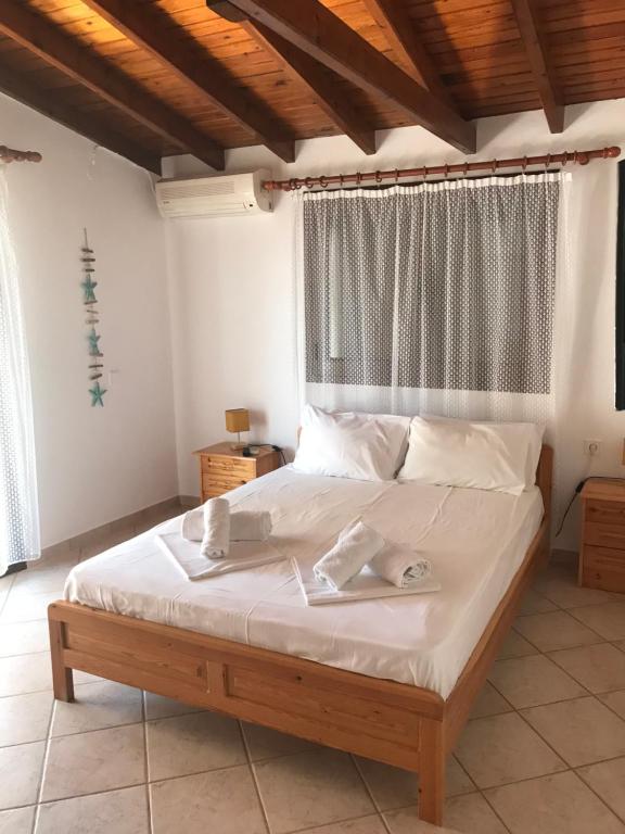 a bedroom with a bed with white sheets and a window at Nikos & Panagiota in Vourvourou