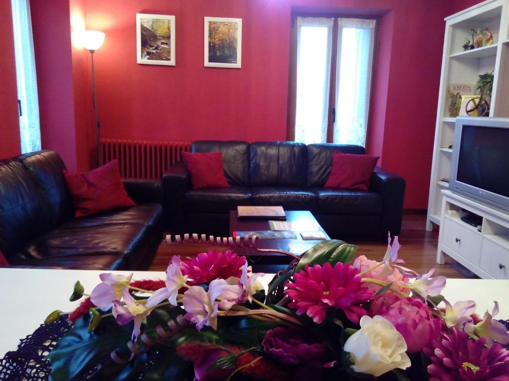 - un salon avec un canapé et une table fleurie dans l'établissement Apartamentos Rurales Imaz Etxea - Urbasa, à Olazagutía