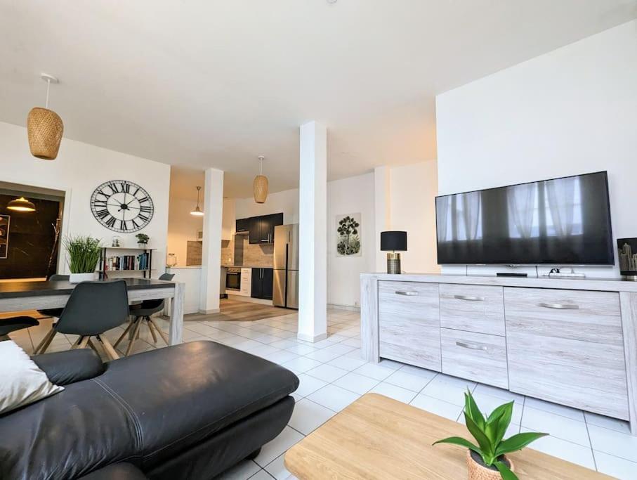 - un salon avec un canapé et une grande télévision dans l'établissement Le Cotti, à Béziers