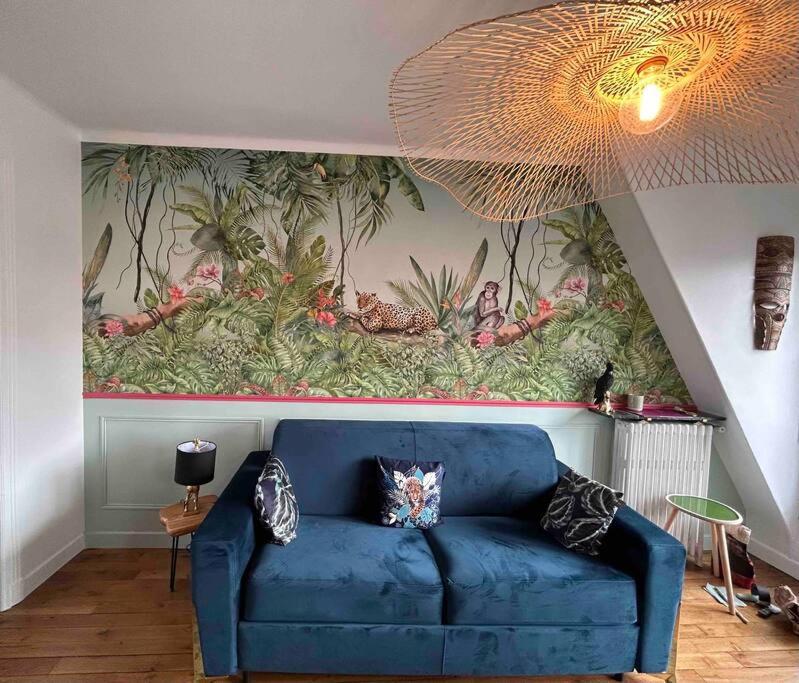 - un canapé bleu dans le salon orné d'une peinture murale dans l'établissement Studio Neuf, Calme, Lumineux, 8e etage, à Paris
