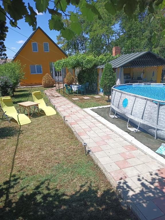 a backyard with a pool and chairs and a house at La Prietenicu in Murighiol