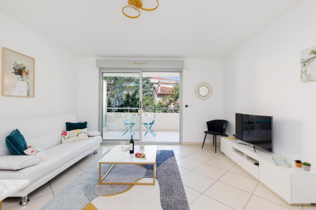 un salon blanc avec un canapé et une télévision dans l'établissement Fleury Home YourHostHelper, à Cannes