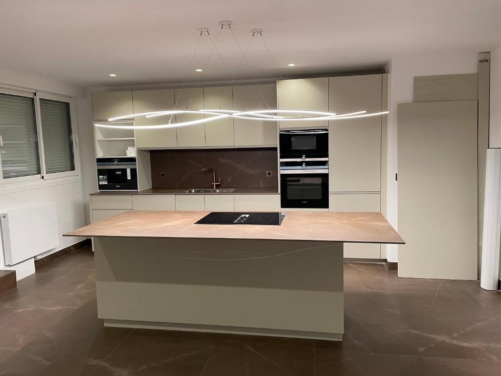 une cuisine avec des placards blancs et un grand îlot dans l'établissement Superbe appartement refait avec terrasse, à Neuilly-sur-Seine