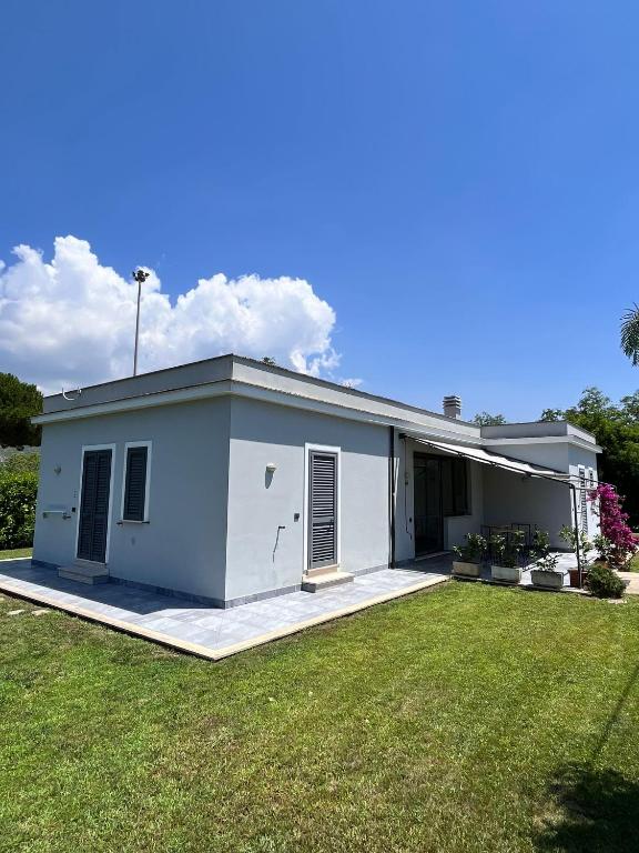 a small white house with a grass yard at La Flacca Rooms in Sperlonga