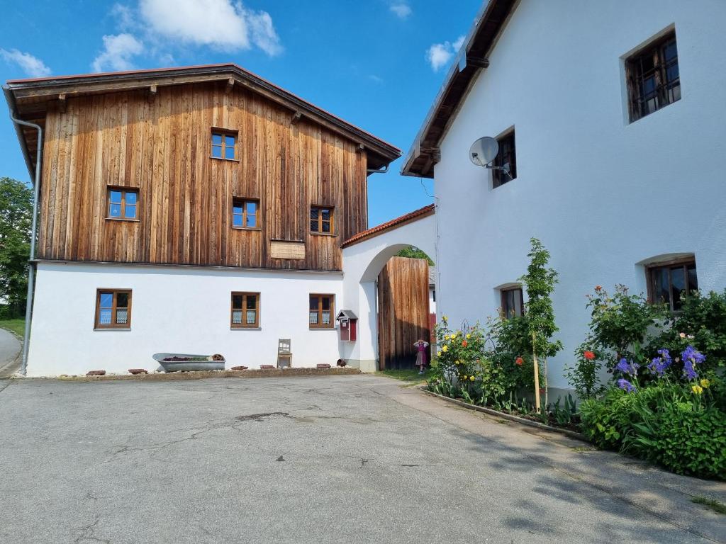 a large white building with a wooden roof at Ferienhaus Ederhof - Idyllischer Vierseithof, kinder- und hundefreundlich, Referenzen auf FeWo-direkt nachlesbar in Aidenbach