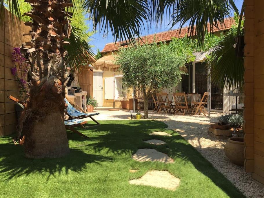 un jardin avec un palmier et une maison dans l'établissement Charmante maison, à Saint-Cyr-sur-Mer