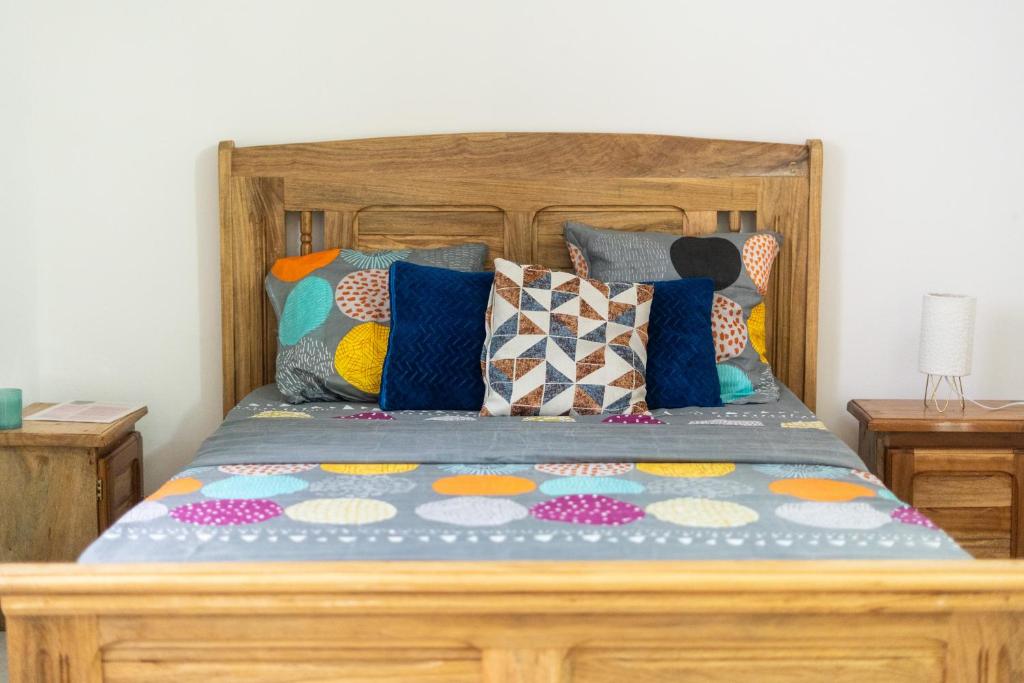 a bed with a wooden frame with colorful pillows at Charmant appartement Avorbam près de Bâti plus in Libreville