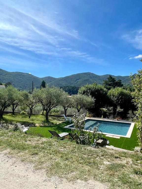 - une piscine dans un champ planté d'arbres et de montagnes dans l'établissement Le Maëlia gîte 5 étoiles, à Nyons