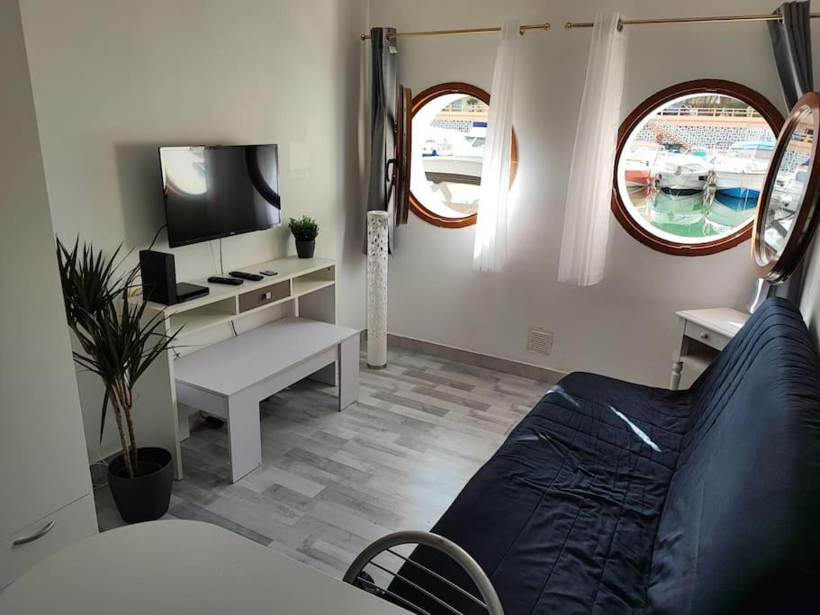 - un salon avec un lit, une télévision et une fenêtre dans l'établissement Studio Les pieds dans l'eau, à Mandelieu-la-Napoule