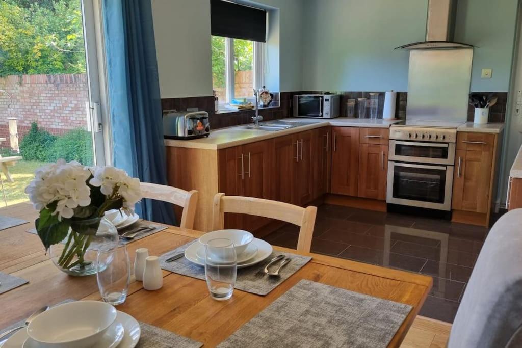 a kitchen with a wooden table with a vase of flowers at Windsor property near Legoland with free parking in Windsor