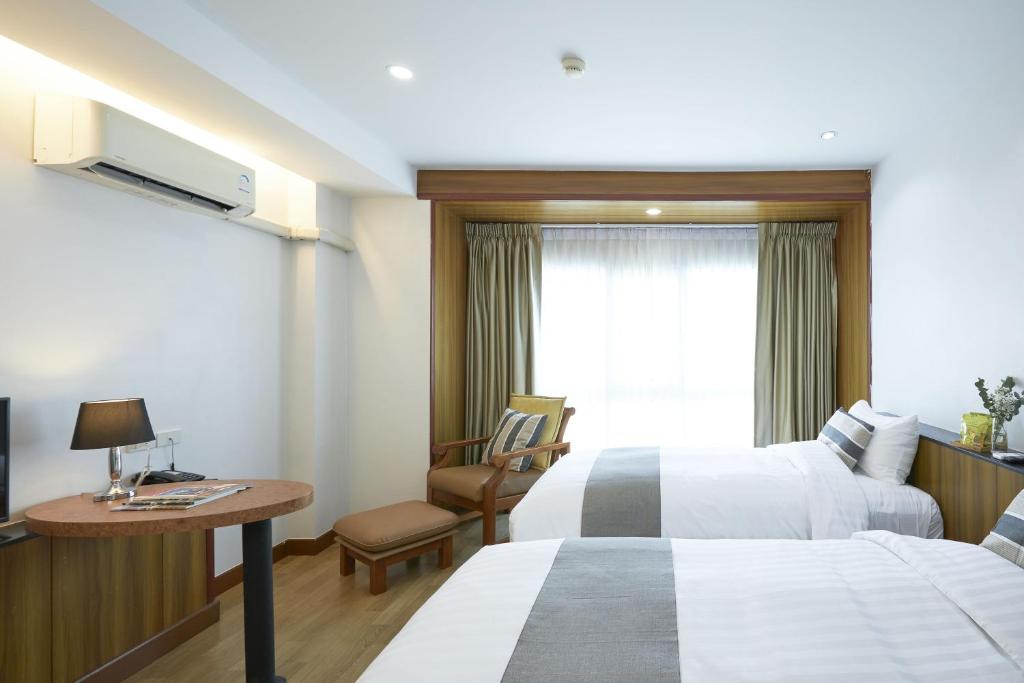 A twin room with two beds, a small table, armchair, desk lamp and curtained window.
