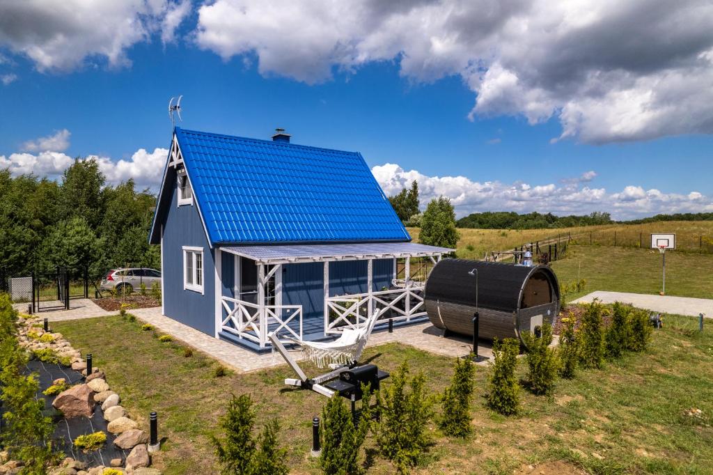 a small blue house with a blue roof on a field at Kaszubskie Klimaty Niebieski Domek in Kościerzyna
