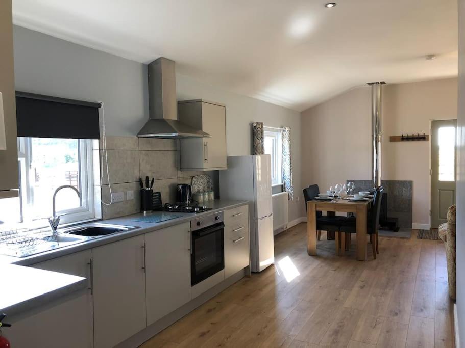 a kitchen with white cabinets and a wooden floor at Nightjar Lodge - Adults Only in Lackford