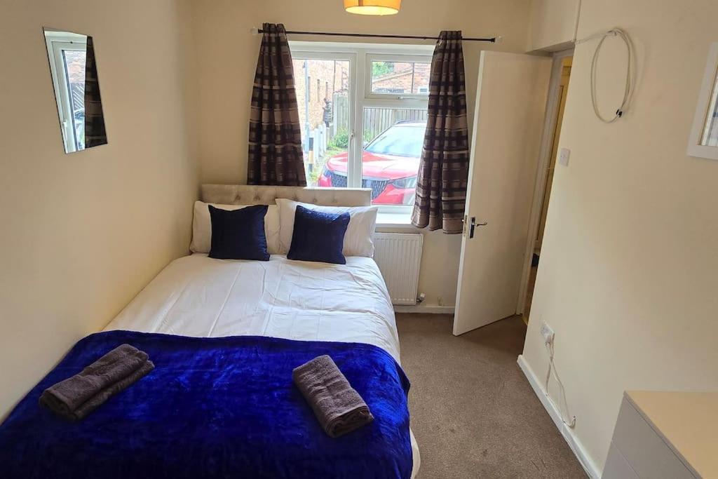 a bedroom with a bed with a blue blanket and a window at Eastpark 5 bdrms Walk to O2 Apollo and City in Manchester