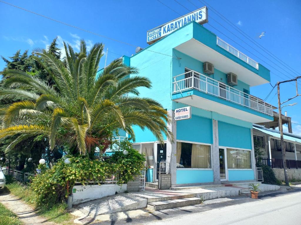 a blue building with a palm tree in front of it at Karagiannis in Keramoti