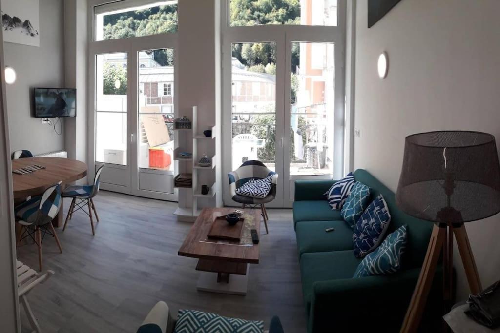 un salon avec un canapé vert et une table dans l'établissement Aigle-Royal Cauterets, appartement RDC 4-6 pers, à Cauterets