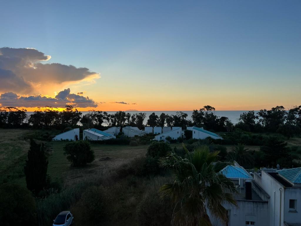 un coucher de soleil sur un champ avec des maisons et des arbres dans l'établissement Duplex vue mer à Piana Verde Canale-di-verde, à Canale-di-Verde