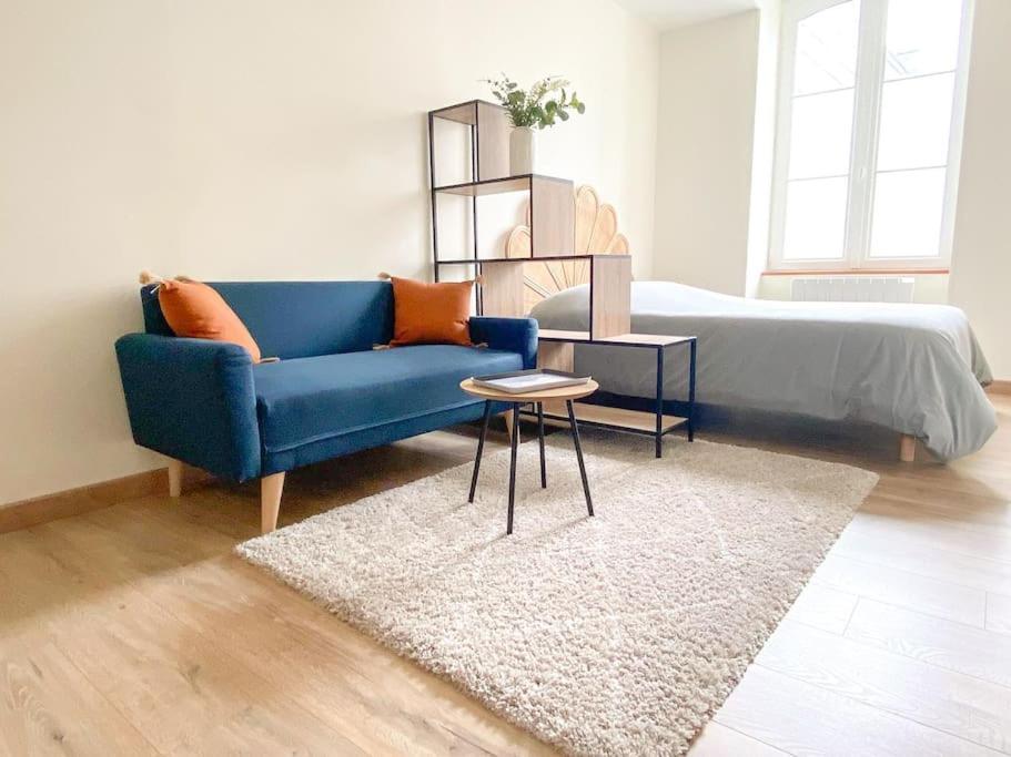 a living room with a blue couch and a bed at Studio coeur de ville paisible in Alençon