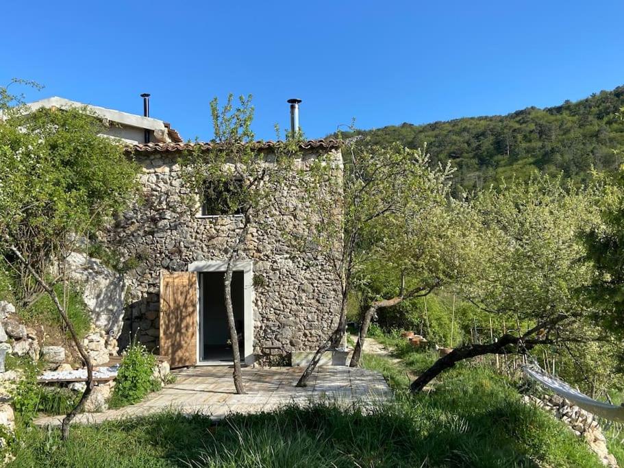 un ancien bâtiment en pierre avec une porte dans un champ dans l'établissement Espace Bergerie La maison d'Hélène, à Peille