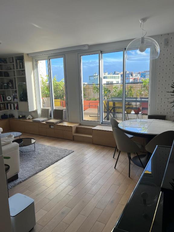 - un salon avec une table, des chaises et une grande fenêtre dans l'établissement Magnifique appartement Terrasse Paris, à Paris