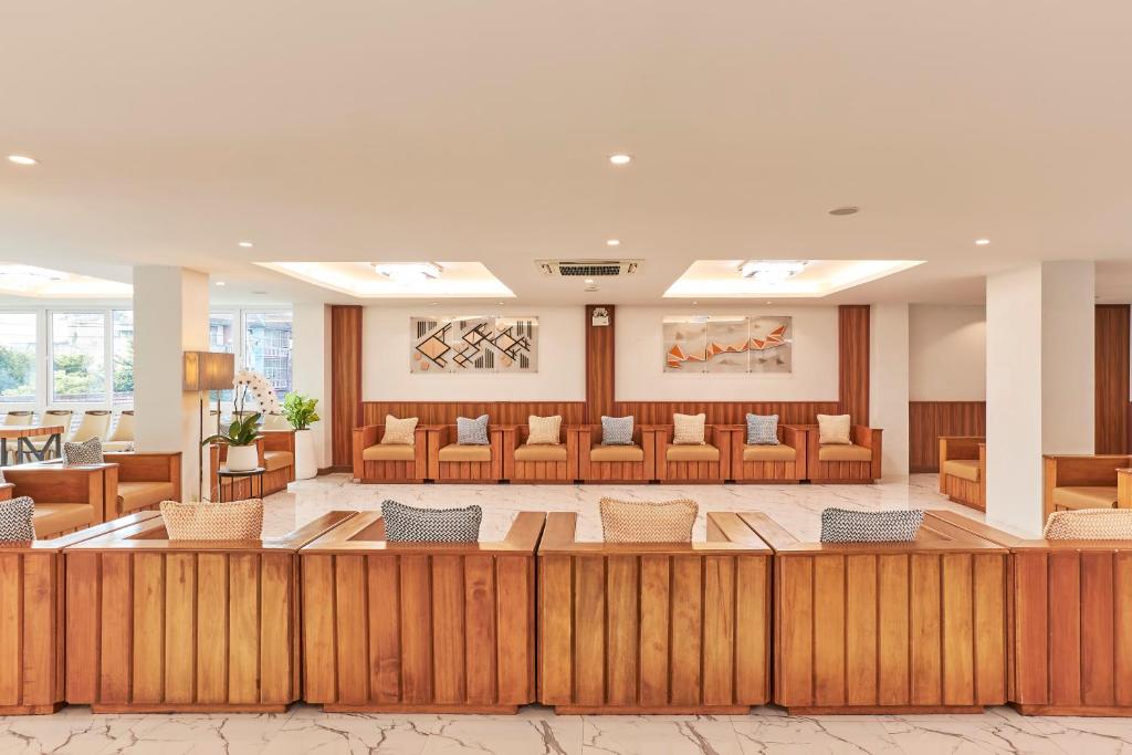 A warm hotel lobby with a long wooden reception counter and lounge seating.