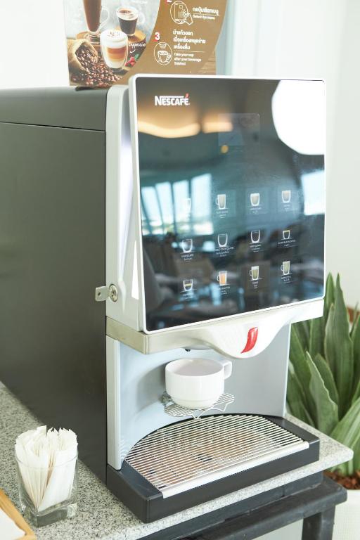 A self-service Nescafé coffee machine with a cup ready beneath the dispenser.