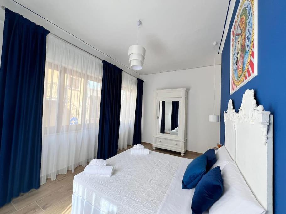 a white bed with blue pillows in a bedroom at Casa Vacanze Tirreno in Trabia