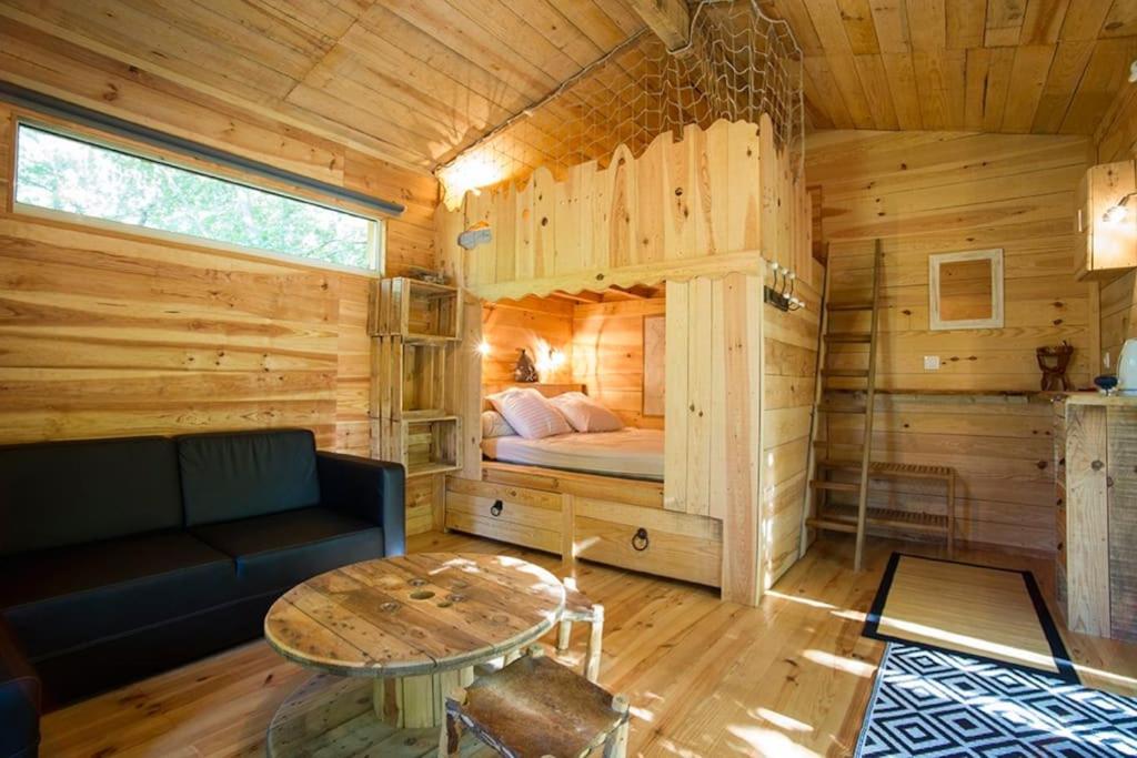 Cette chambre comprend un lit dans une cabane en bois. dans l'établissement JOLIE CABANE BOIS SOUS LES CHENES Hourtin bourg, à Hourtin