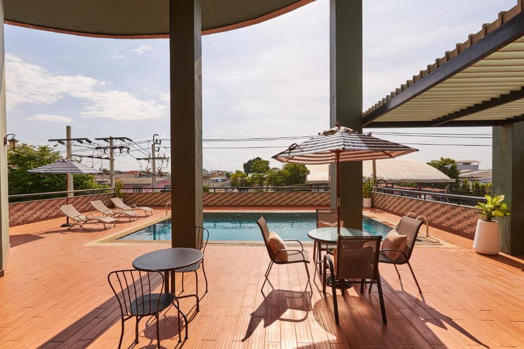 A rooftop pool terrace with café tables, chairs, loungers and striped umbrellas.