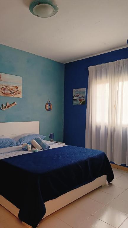 a bedroom with a bed with blue walls and a window at LA TERRAZZA SUL MARE camera fronte mare&vicino aereoporto SICILIAN VINTAGE STYLE SEASIDE ROOM in Cinisi
