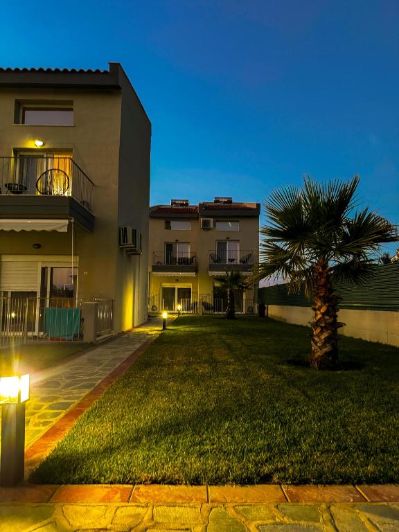 a building with a palm tree in front of a yard at Charisma Resort in Ímeros