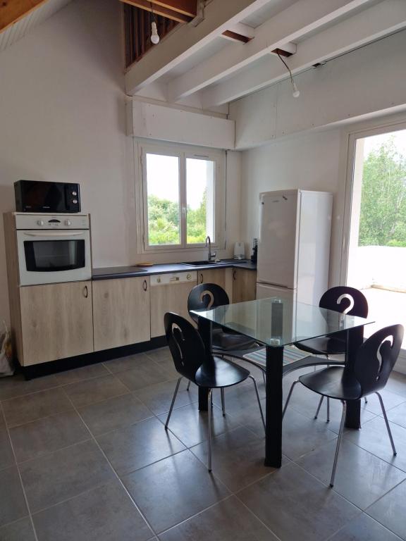 une cuisine avec une table en verre et des chaises noires dans l'établissement Maison 10 min de la plage, à Saint-Gildas-de-Rhuys