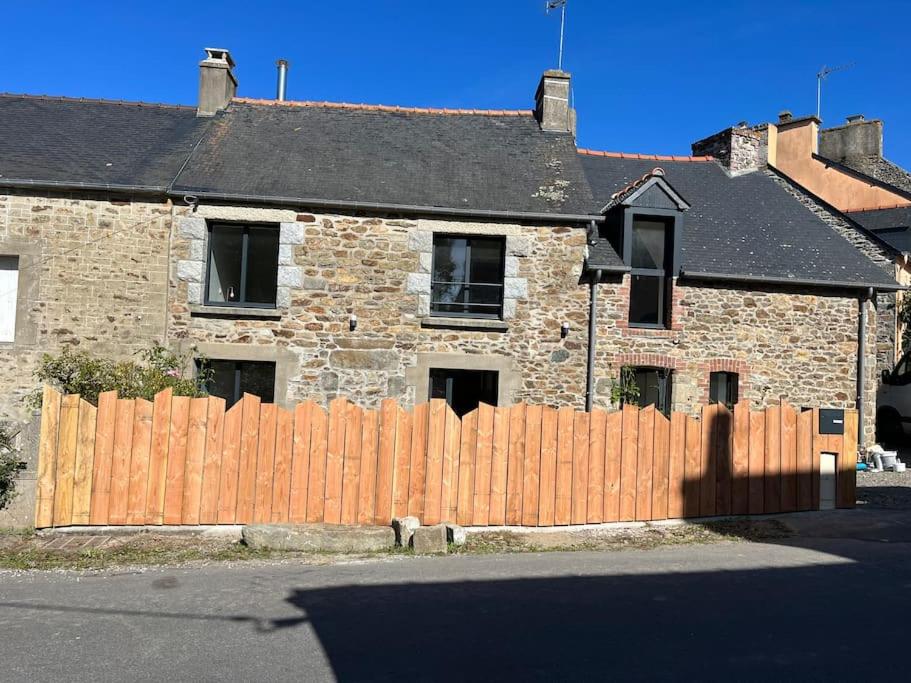 une maison en briques avec une clôture en bois devant elle dans l'établissement Maison de Pays rénovée, à Pleurtuit