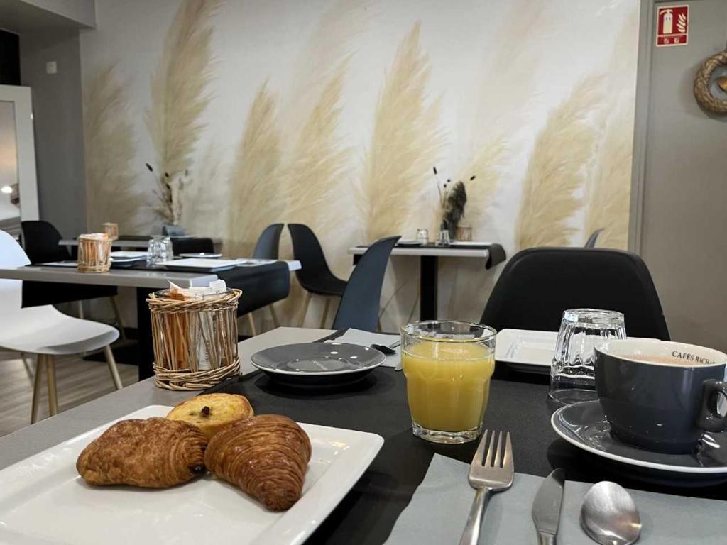a table with a plate of bread and orange juice at Hotel Best Western La Mare Ô Poissons in Ouistreham