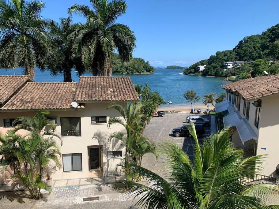 a view of a house and a beach with palm trees at Casa 3 qtos beira mar praia exclusiva e piscina in Angra dos Reis