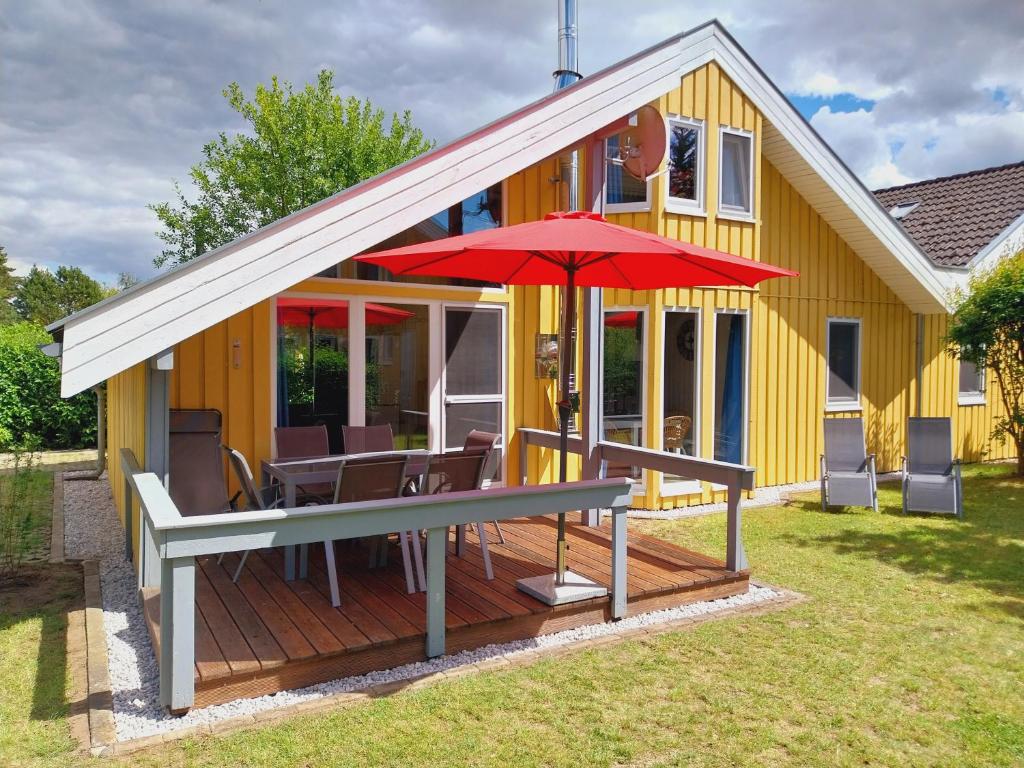 una casa con terraza y sombrilla roja en Wildgans 136, en Mirow