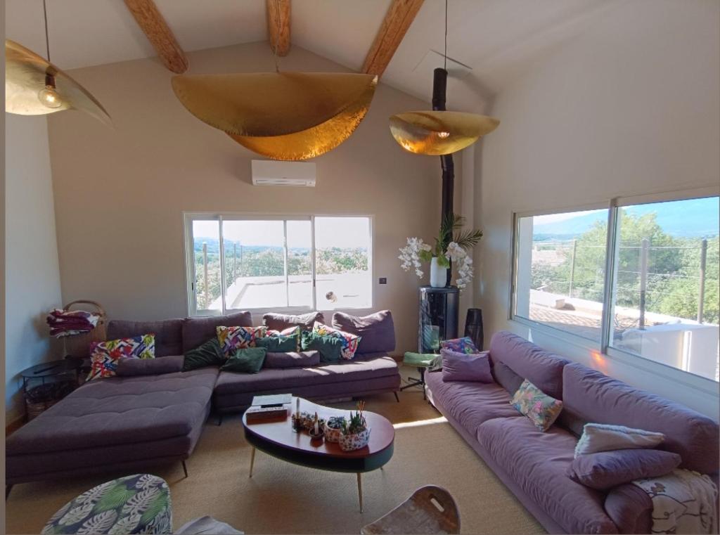 a living room with purple couches and a table at Là où le Ciel est né Beau mas pierres et contemporain sur grande propriété vue Mont Ventoux dentelles de Montmirail in Blauvac