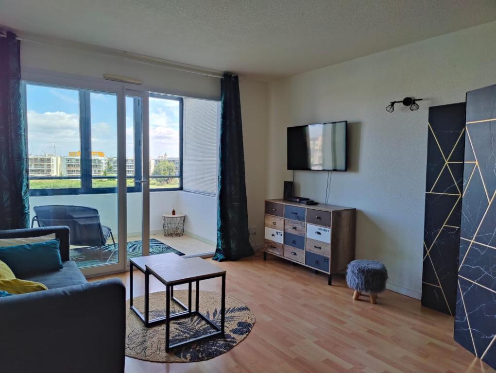 un salon avec un canapé et une télévision dans l'établissement L'Escapade 1 chambre-parking-piscine, à La Rochelle