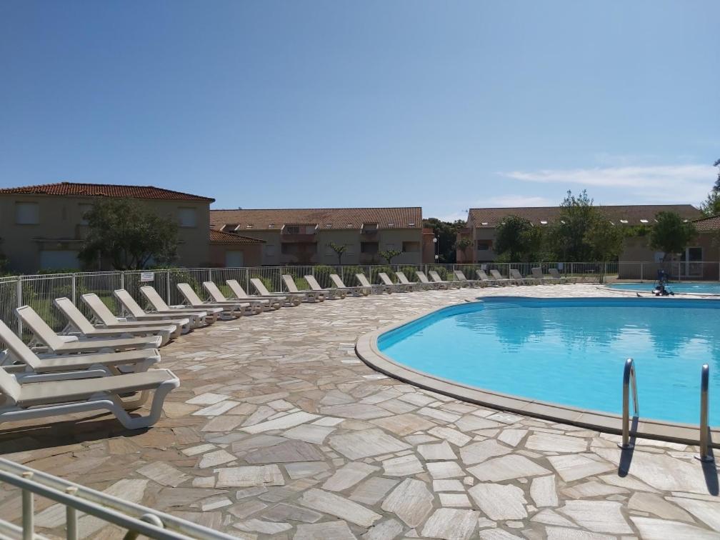 une piscine avec des chaises longues à côté d'un bâtiment dans l'établissement Ville melody, à San-Nicolao