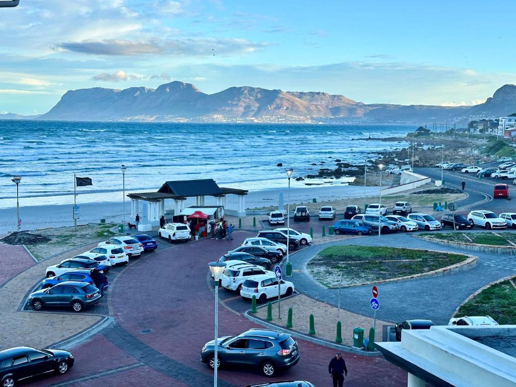 a parking lot with cars parked next to the ocean at Muizenberg Surfers corner and Beach Paradise in Cape Town