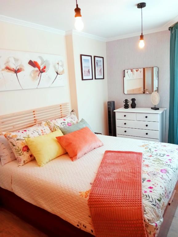 a bedroom with a bed with colorful pillows and a dresser at PAUTANA, céntrico y a pocos minutos de Vigo in Cangas de Morrazo